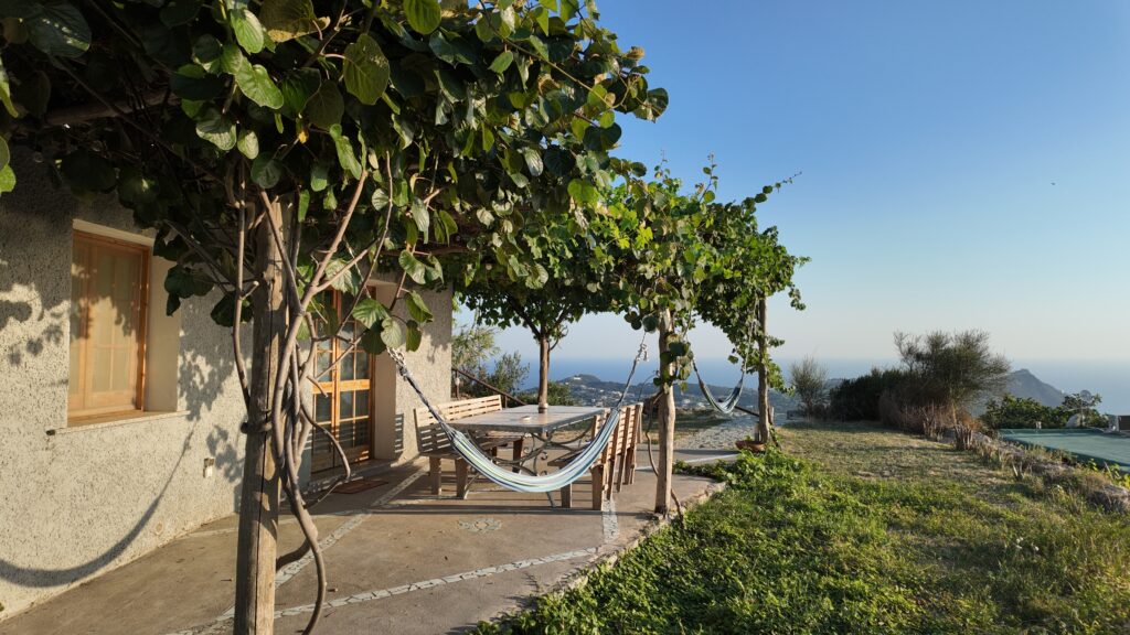 La Casa Familiare del vigneto Fiorola con due amache e il pergolato e il mare sullo sfondo